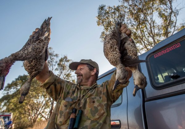 A photo of a hunter with dead ducks.