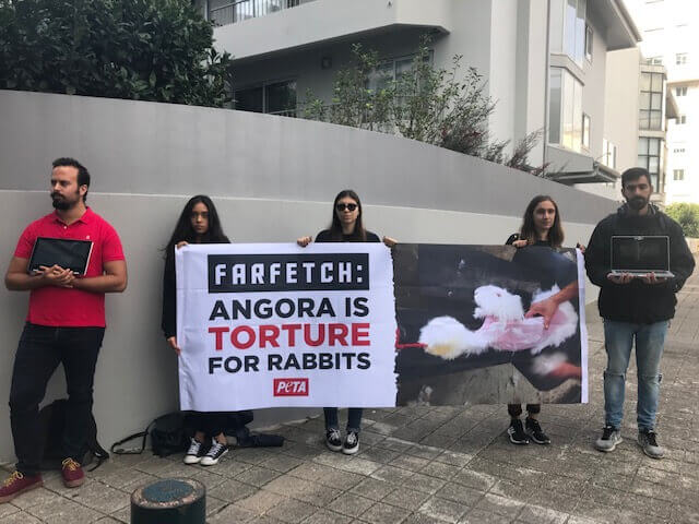 protesters hold a sign that reads" Farfetch : Angora is torture for rabbits."