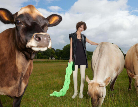 Woman wears Co Exist Collection while standing with cows in a field