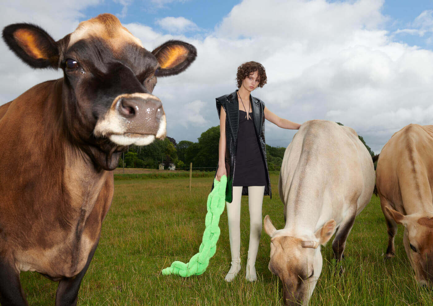 Woman wears Co Exist Collection while standing with cows in a field