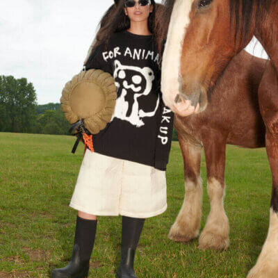 Woman wears Co Exist collection while standing beside a horse