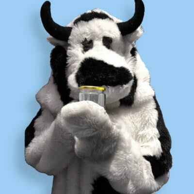 a person in a cow costume holding a jar