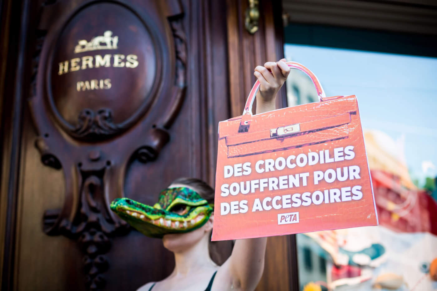 A protester wearing a crocodile mask outside Hermès in Paris.