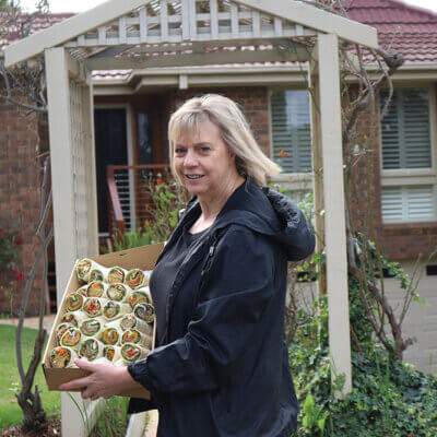 A woman stands in front of an iconic Ramsay Street house