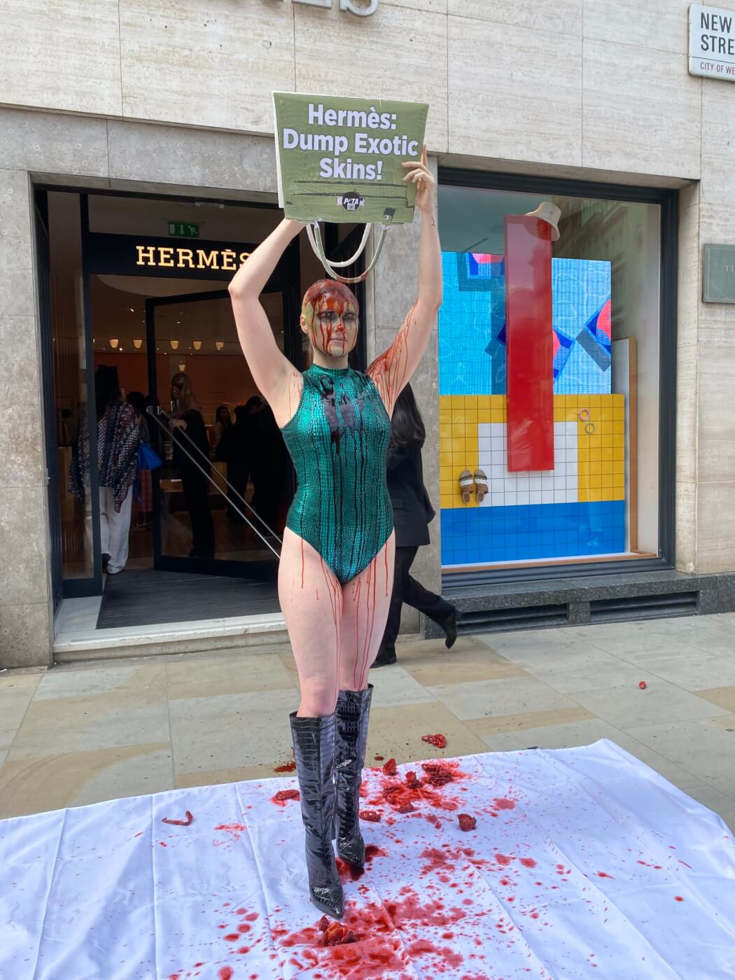 London, England, UK. 26th July, 2023. Vegan activist TASH PETERSON drench  herself in fake blood and guts from a mock croc bag in front of London's  flagship HermÃ¨s store, in a push