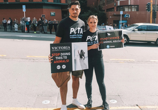 A photo of two activists protesting outside Victoria University of Wellington.