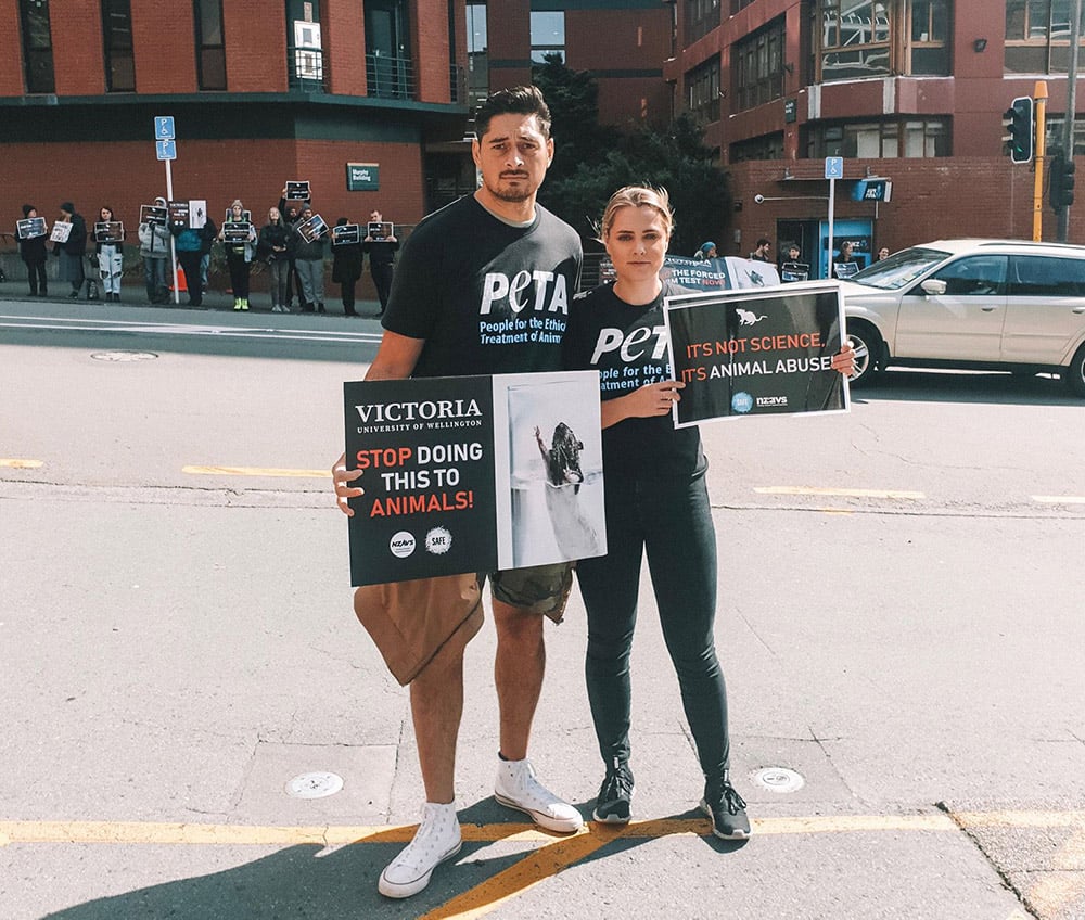 A photo of two activists protesting outside Victoria University of Wellington.