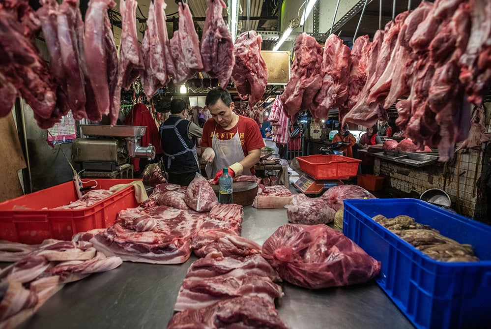 Vendors chop slabs of meat and hang them for sale at a wet market in Taipei.