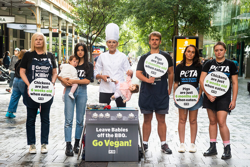 activists stand around a barbecue with a doll