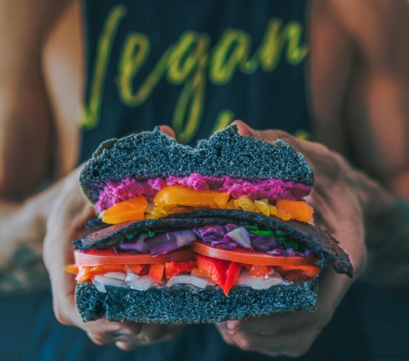 person holding burger wearing vegan shirt