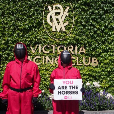 protesters wearing pink suits with black masks from Squid Game