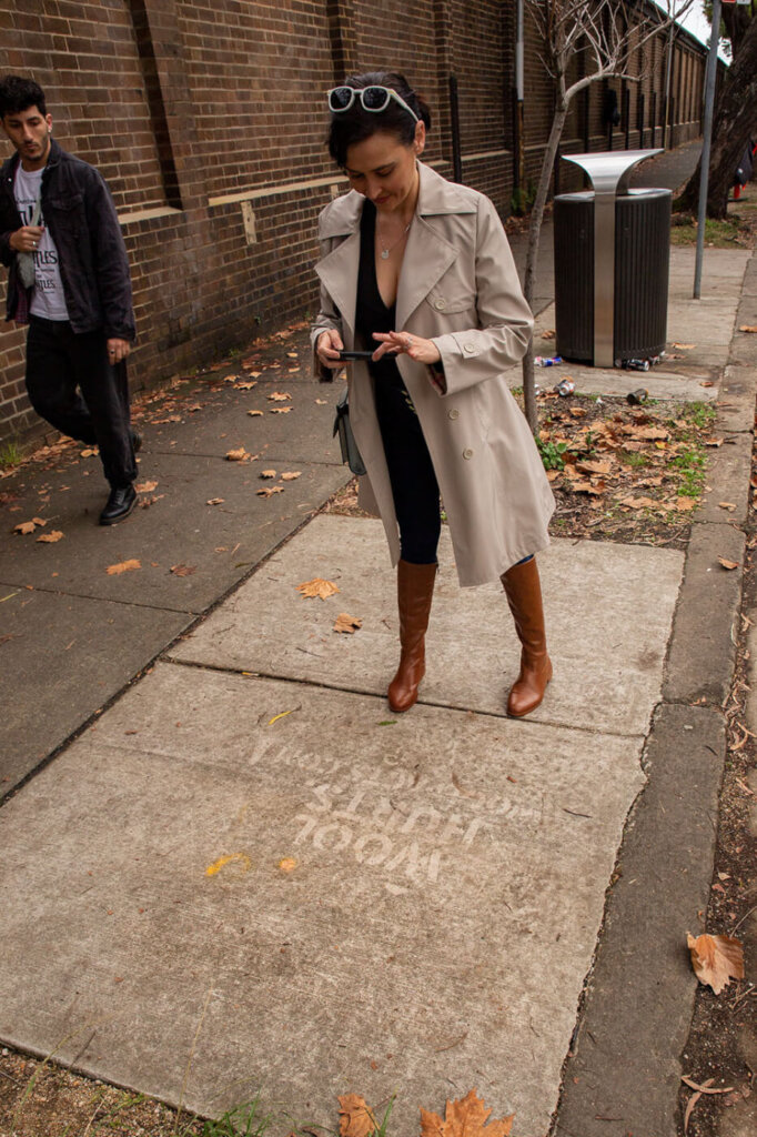 a woman takes a photo of a street stencil at Australian Fashion Week in Sydney
